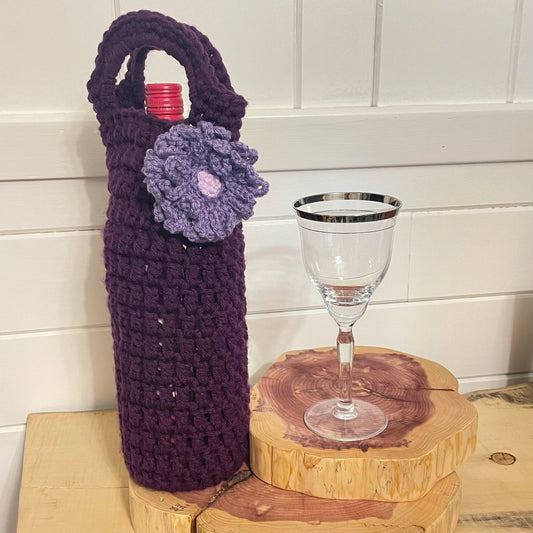Purple & Lilac Floral Wine Bottle Carrier Holder Gift Bag Crochet Knit Embellished Hand Crafted--displayed with a wine bottle inside next to a wineglass