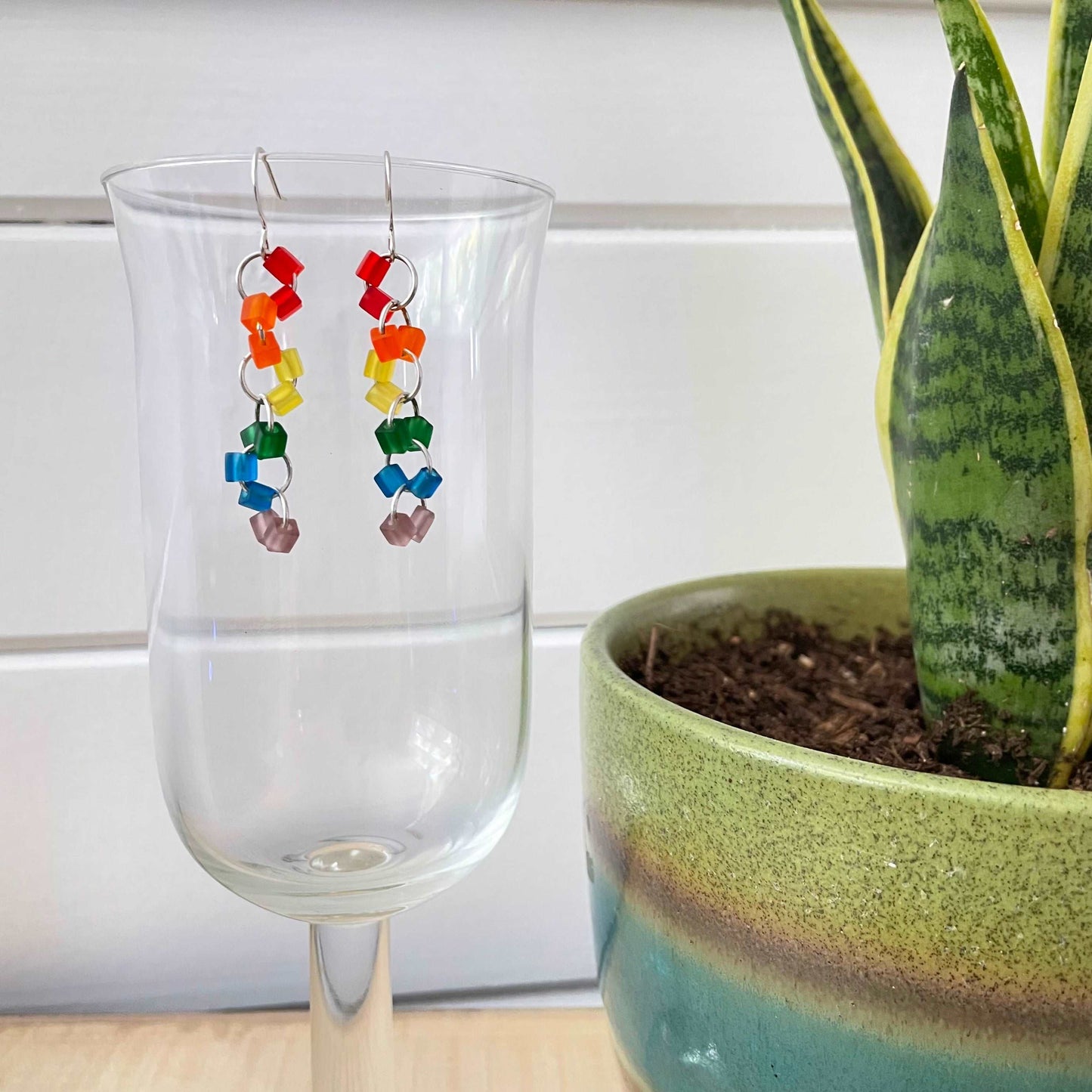 view of earrings hanging against clear background to showcase colorful frosted beads and larger size jump rings