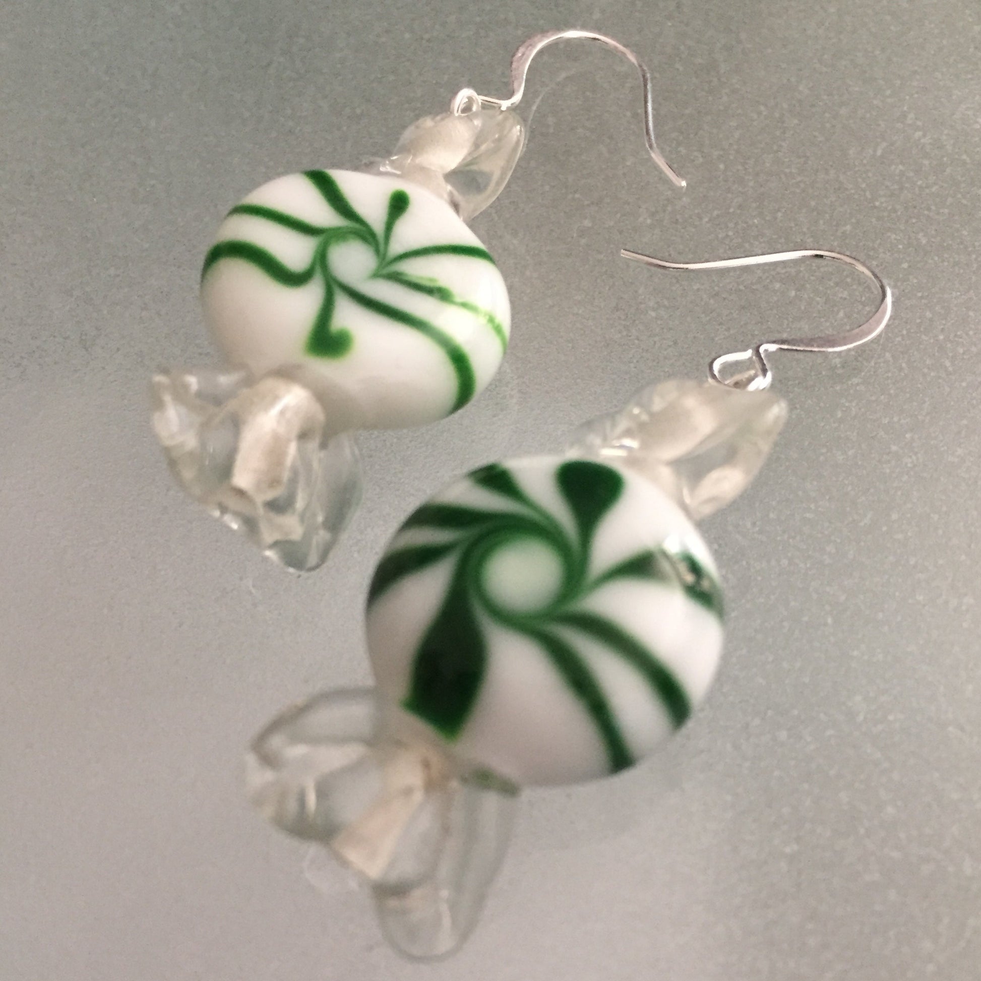 close up of Green Peppermint Candy Earrings 2" Swirled White Clear Green Glass Holiday Whimsy Fun Playful Stocking Filler