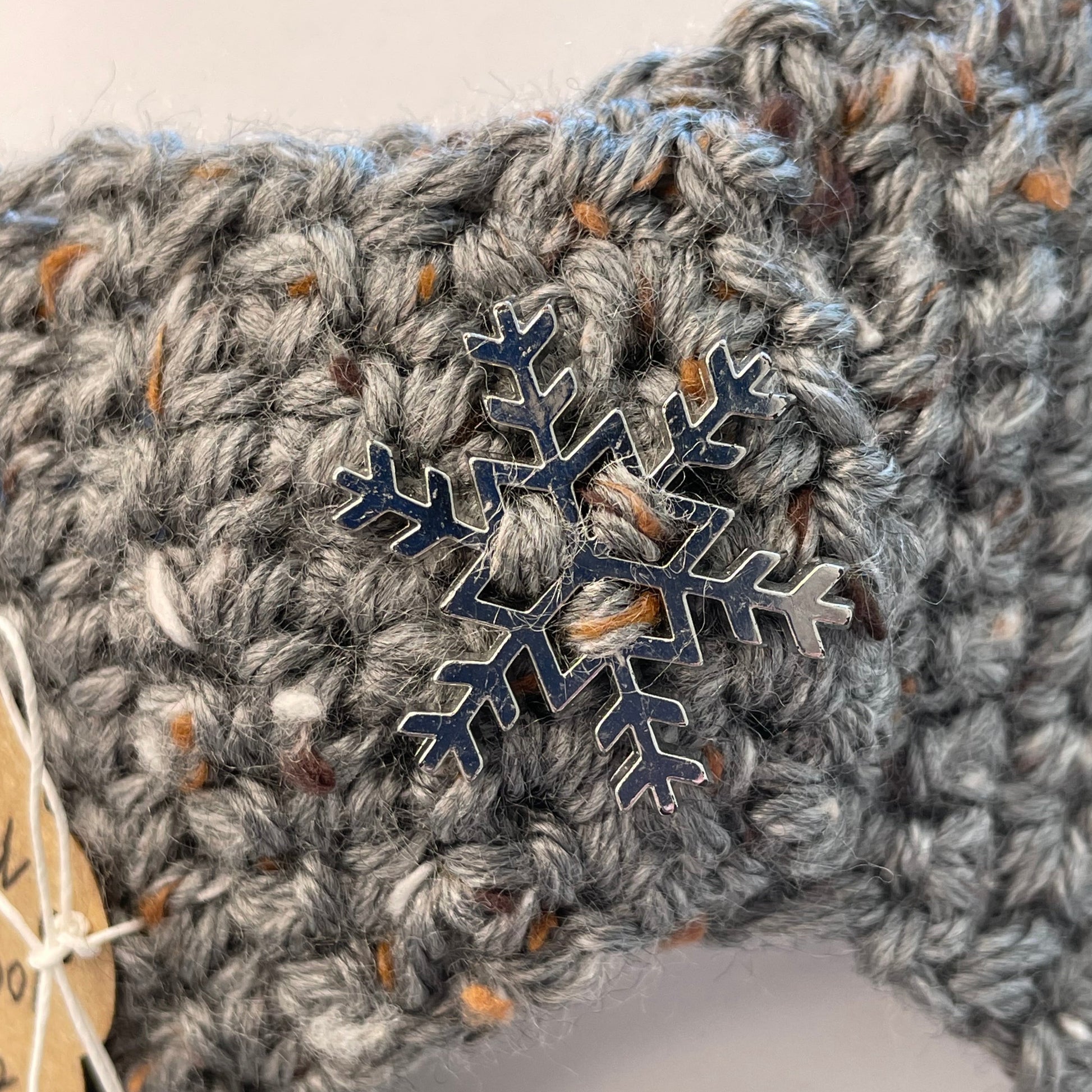 closeup of metal snowflake accent on ear warmer