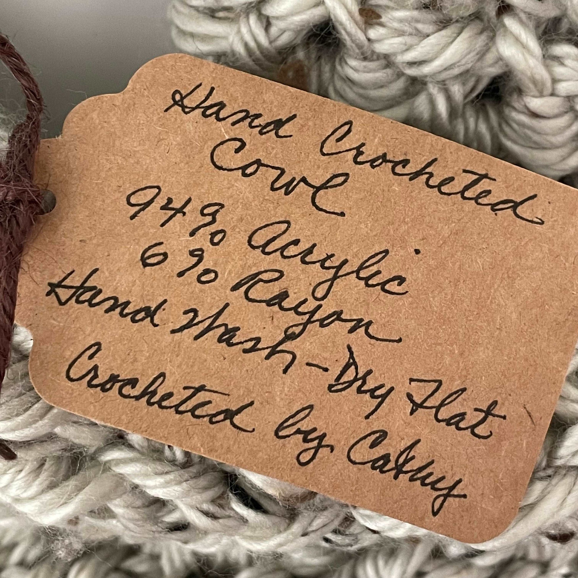 close up of handwritten tag--hand crocheted cowl 94% acrylic 6% rayon hand wash dry flat crocheted by cathy